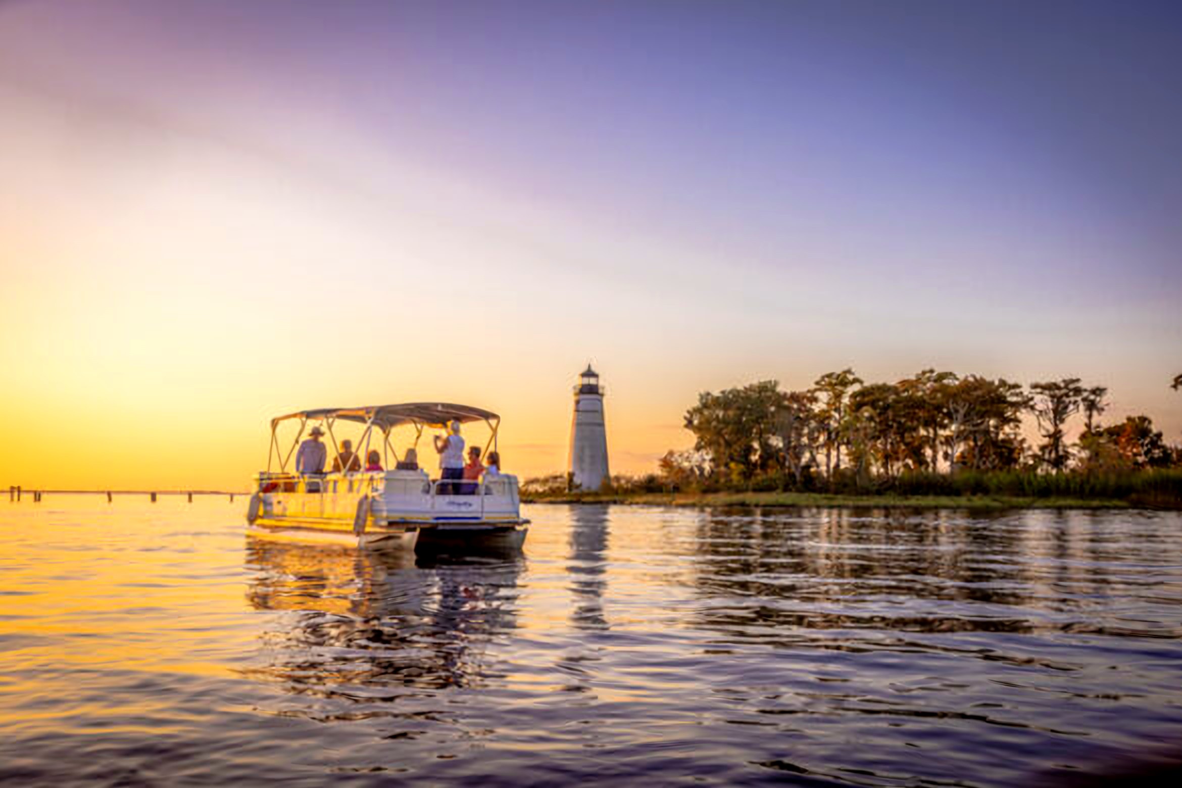 Pontoon boat at sunset by the Tchefuncte River lighthouse in Madisonville